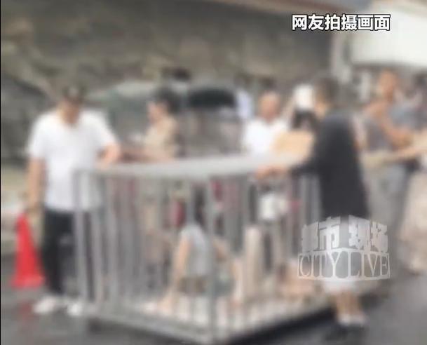 两女子与狗被关进钢笼游街,笼顶挂着偷人的牌子:摆拍低俗场景博流量